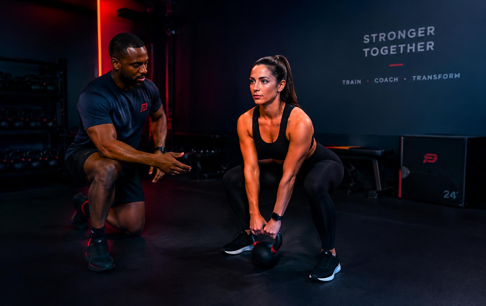 Coach guiding a client through a kettlebell exercise